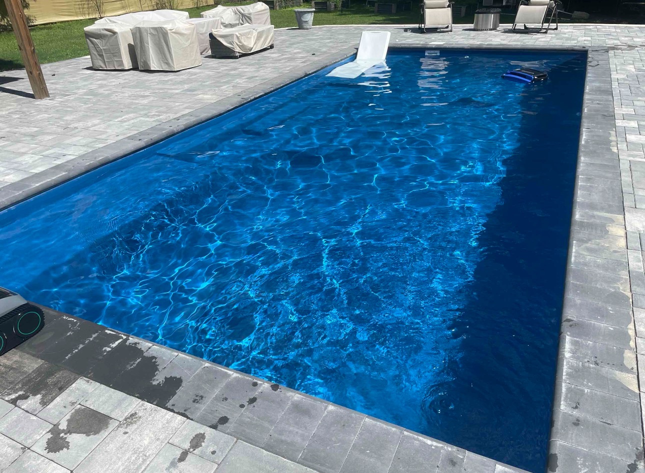 Clear rectangular residential pool with blue water and paver deck.