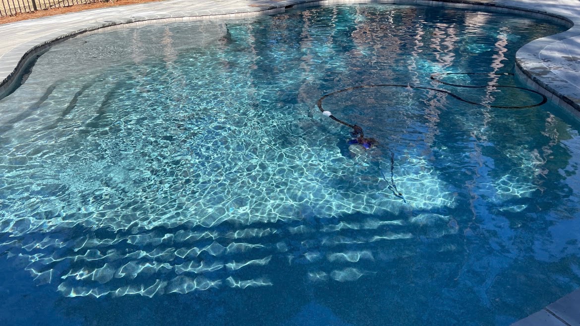Clear residential pool water with sunlight reflections.