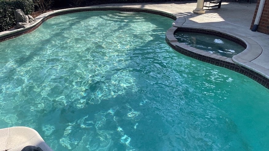 Clear residential pool with attached spa.