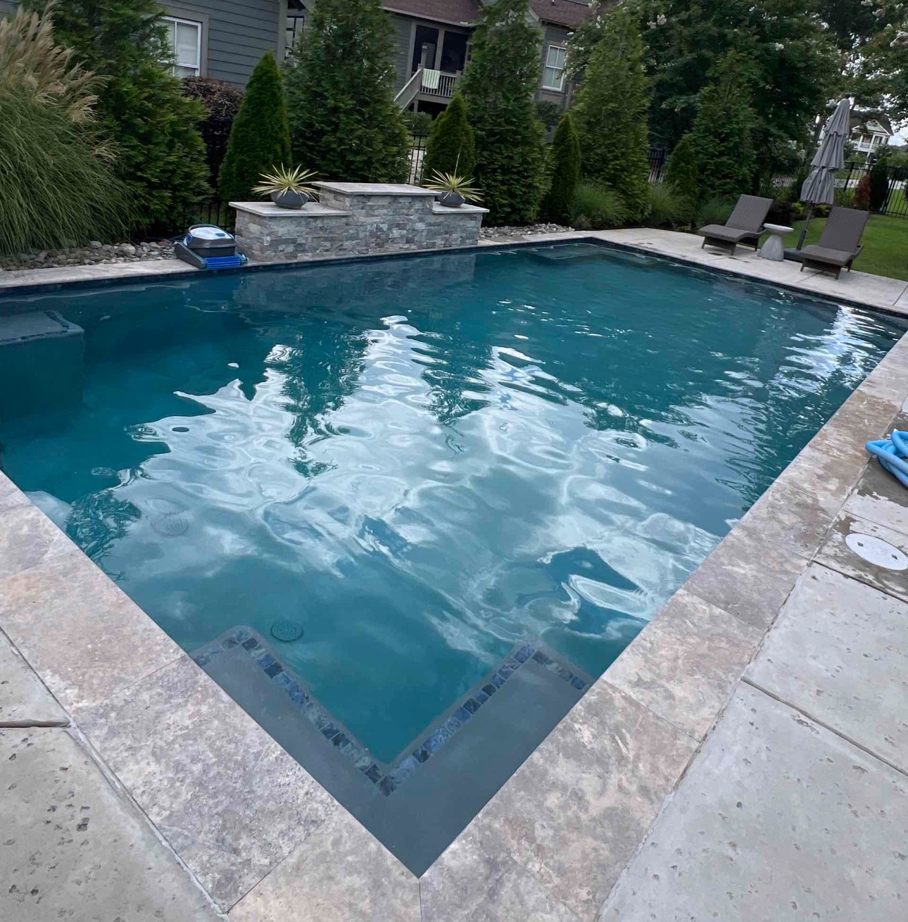 Clear residential pool with raised stone wall.